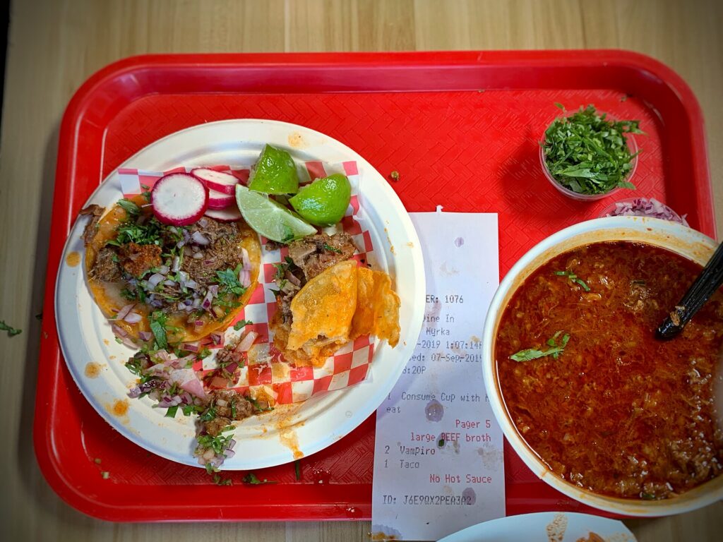 Birria tacos served with a cup of consommé for dipping