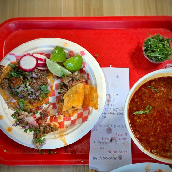 Birria tacos served with a cup of consommé for dipping