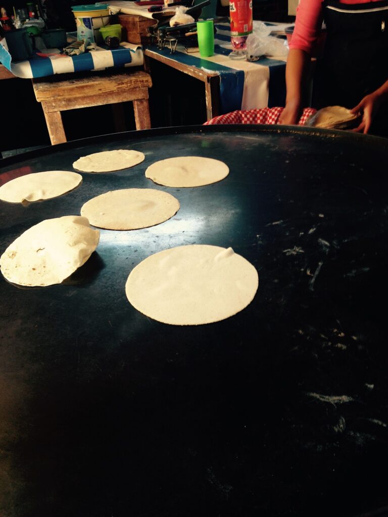 Corn tortillas cooking on a comal